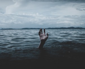 a hand lifted up in a sea by someone drowing