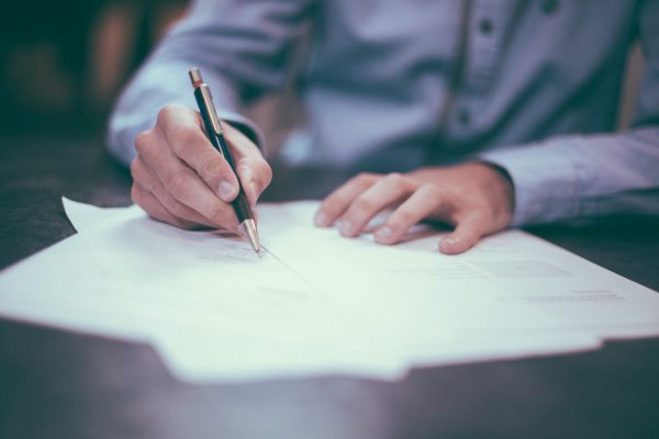 A pair of hands writing on paper with a pen